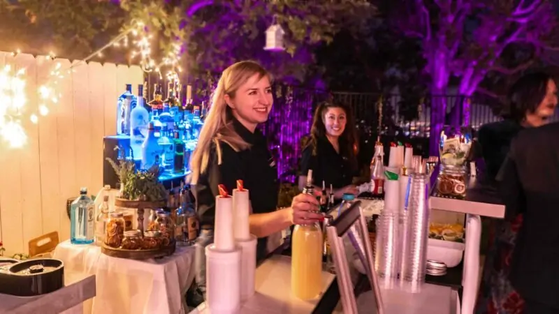 a bartender serving a cocktail and having conversation with guest Party Shakers
