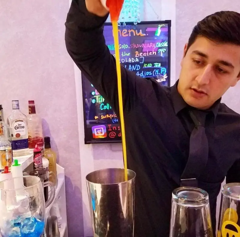 a bartender behind a bar pouring juice into shaker. bartending life movie