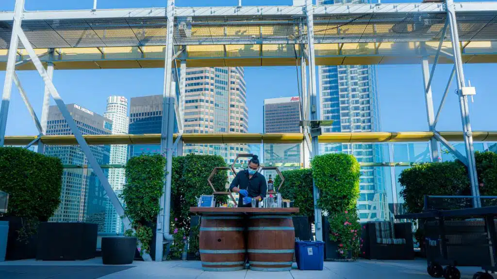 A rustic barrel bar set up at roof top Downtown Los Angeles with bartender in it | Party Shakers